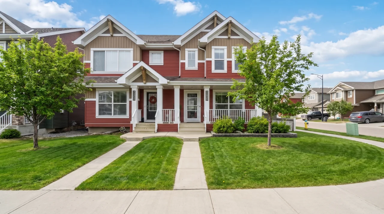 A red and beige duplex with covered front porches on a tree-lined Edmonton street